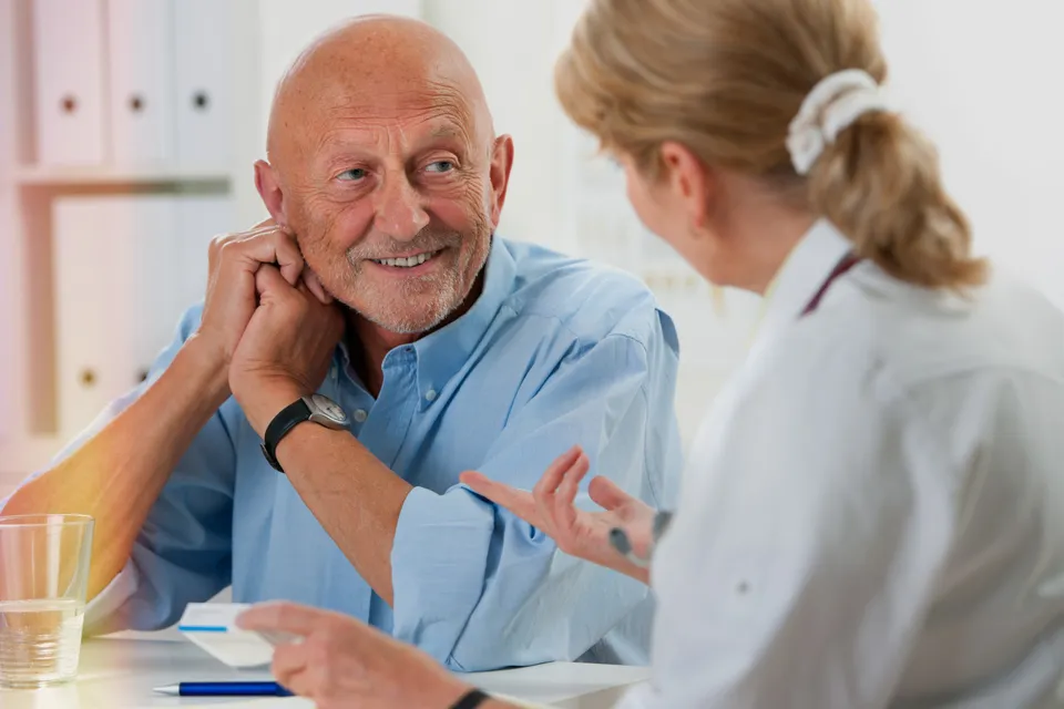 An audiologist talking with a smiling older patient during a consultation